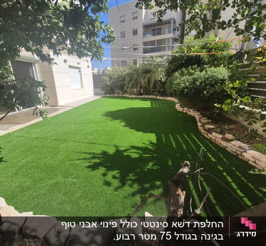 דשא סינתטי מוקף בצמחייה וגבול אבנים